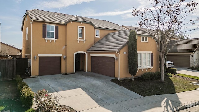 view of front of house featuring driveway, a tiled roof, an attached garage, and stucco siding