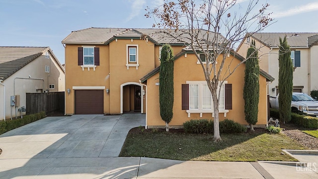 view of front of house with driveway, a tile roof, an attached garage, fence, and stucco siding