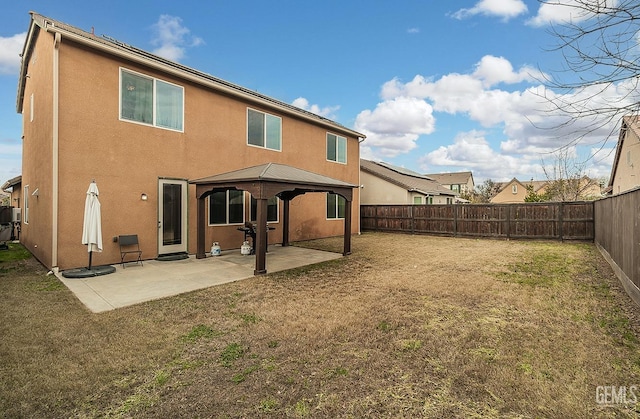 rear view of property with stucco siding, a fenced backyard, a patio area, and a gazebo