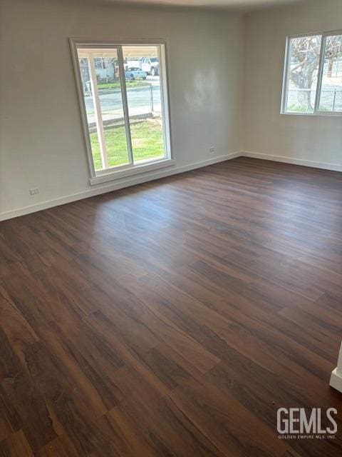 spare room with plenty of natural light, baseboards, and dark wood finished floors