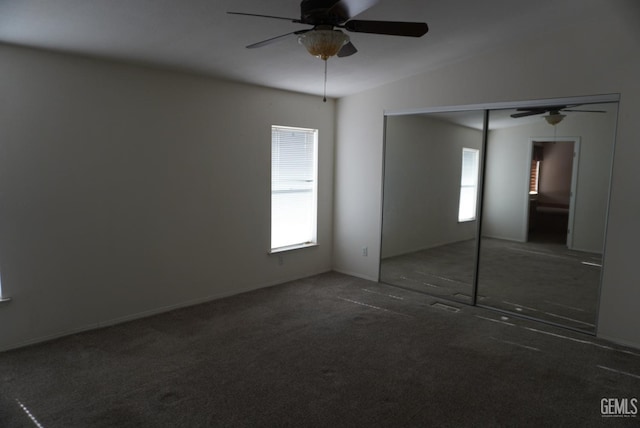 unfurnished bedroom with dark colored carpet, ceiling fan, lofted ceiling, and a closet