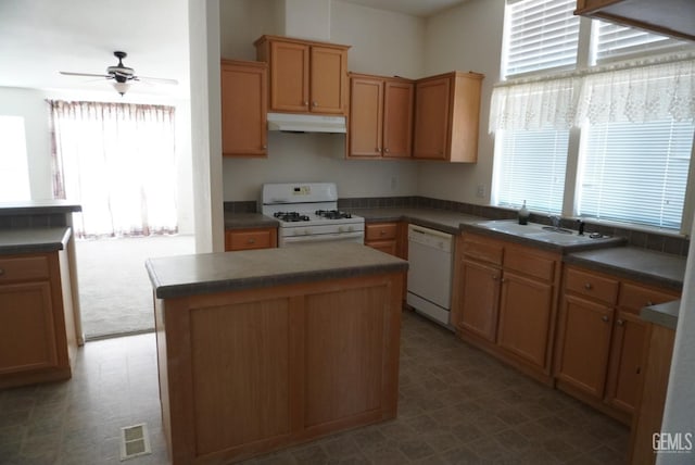 kitchen with white appliances, a center island, ceiling fan, and sink