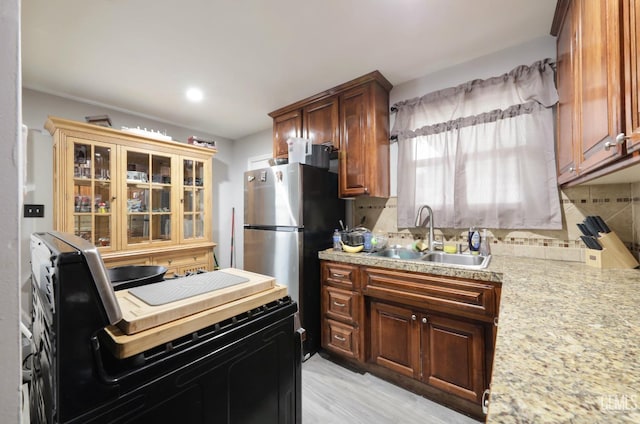 kitchen featuring electric stove, backsplash, a sink, and freestanding refrigerator