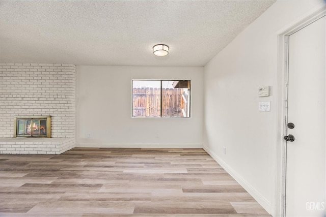 2904 Brock Way, Bakersfield, CA 93306 - unfurnished living room featuring a fireplace, a textured ceiling, light wood-style floors, and baseboards