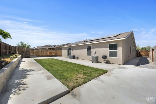 rear view of property featuring a patio area, stucco siding, roof mounted solar panels, and central AC