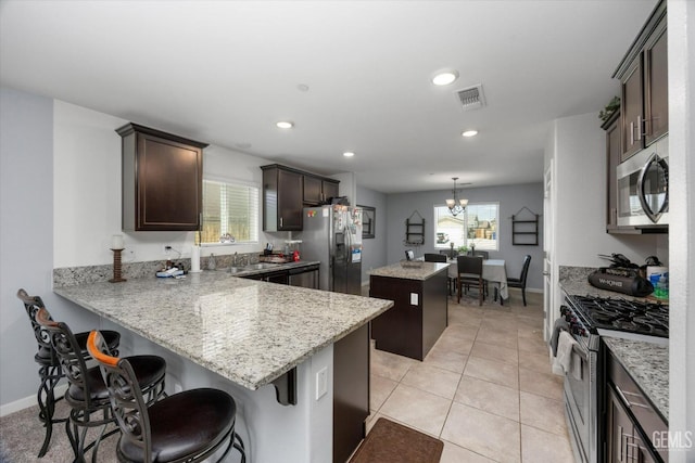 kitchen with stainless steel appliances, a center island, dark brown cabinetry, plenty of natural light, and recessed lighting