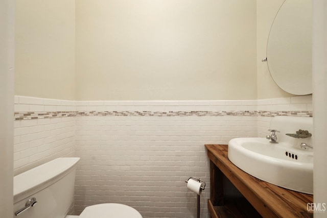 bathroom featuring vanity, tile walls, and toilet