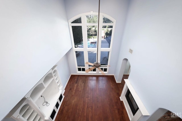 unfurnished living room with dark hardwood / wood-style flooring and a towering ceiling