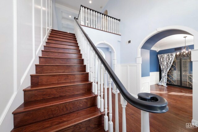 stairs with hardwood / wood-style flooring and a notable chandelier