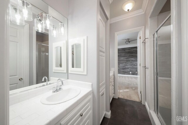 bathroom with vanity, a shower with shower door, and crown molding