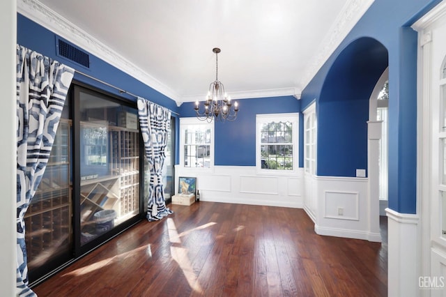 unfurnished dining area with dark hardwood / wood-style flooring, ornamental molding, and a notable chandelier