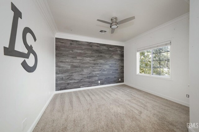 empty room featuring carpet, wooden walls, ceiling fan, and ornamental molding