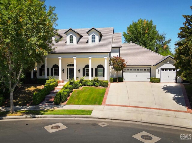 view of front of property with covered porch, a garage, and a front lawn