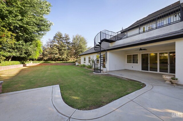 view of yard featuring a balcony, ceiling fan, and a patio area