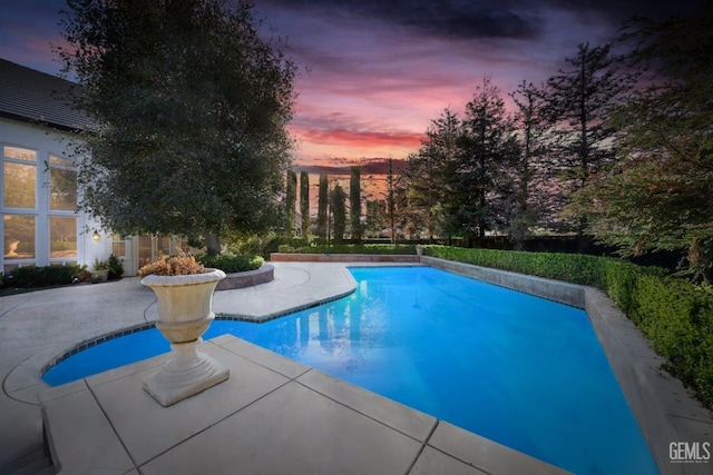 pool at dusk with a patio area