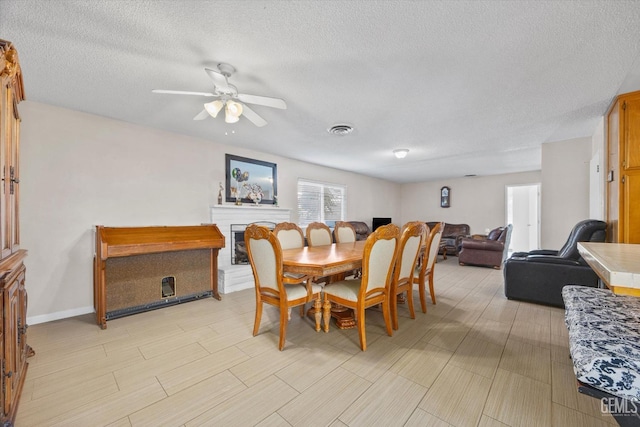 4501 Chadbourn St, Bakersfield, CA 93307 - dining space with a textured ceiling, a ceiling fan, and a fireplace with raised hearth