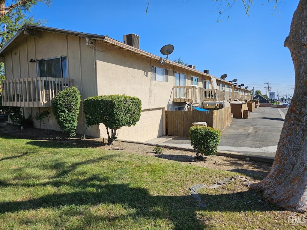 exterior space with central AC unit, a garage, and a yard