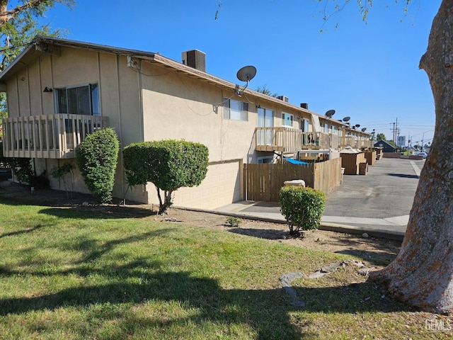 exterior space with central AC unit, a garage, and a yard