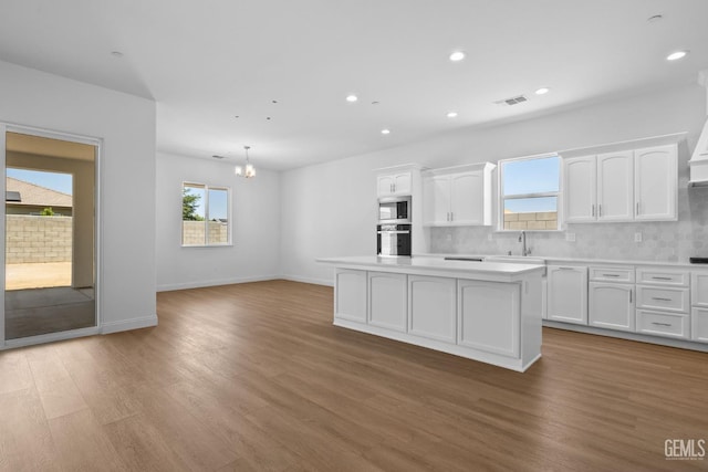 8708 Tamburlane Ct, Bakersfield, CA 93314 - kitchen with stainless steel microwave, oven, a kitchen island, white cabinets, and tasteful backsplash