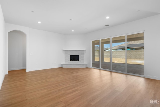 8708 Tamburlane Ct, Bakersfield, CA 93314 - unfurnished living room with arched walkways, light wood finished floors, a fireplace, and recessed lighting