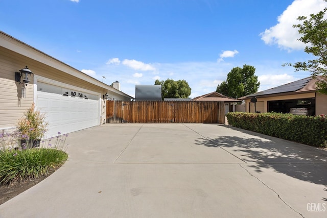 view of side of property featuring fence, concrete driveway, and a garage