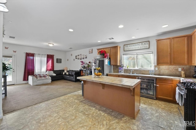 kitchen with range, stainless steel fridge, light colored carpet, wine cooler, and a breakfast bar area