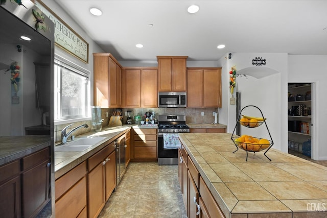 kitchen with sink, tile counters, decorative backsplash, and appliances with stainless steel finishes