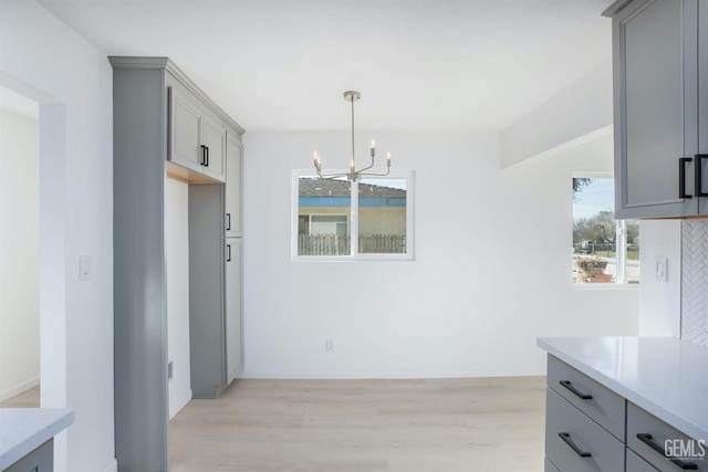 unfurnished dining area featuring plenty of natural light, a chandelier, and light wood-type flooring