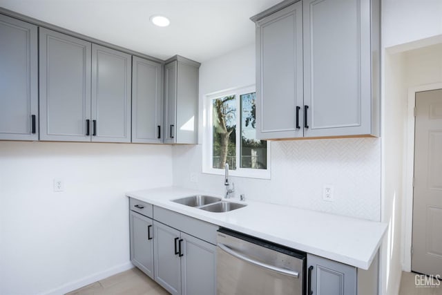 kitchen featuring sink, tasteful backsplash, gray cabinets, dishwasher, and light hardwood / wood-style floors