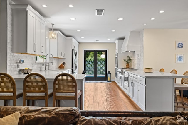 401 Via Carisma, Bakersfield, CA 93309 - kitchen with freestanding refrigerator, a breakfast bar, a peninsula, premium range hood, and a sink