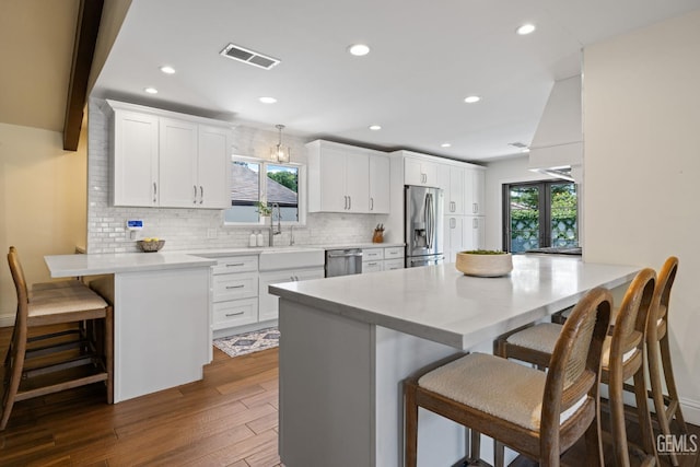 401 Via Carisma, Bakersfield, CA 93309 - kitchen with appliances with stainless steel finishes, a sink, a kitchen bar, dark wood-type flooring, and backsplash