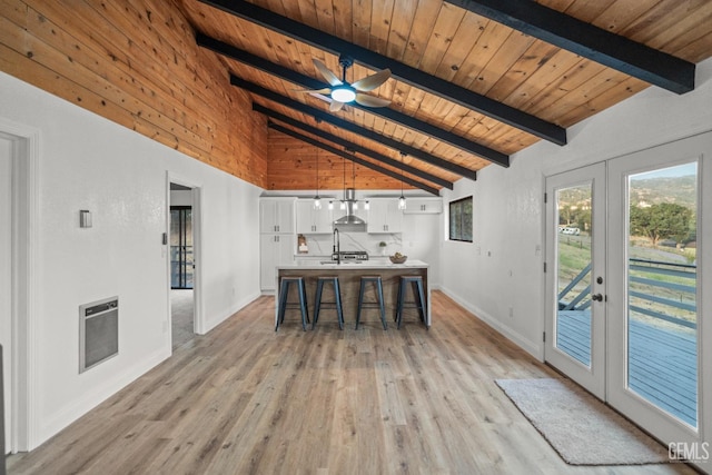 24501 Pueblo Ct, Tehachapi, CA 93561 - kitchen with heating unit, light wood-style floors, white cabinets, a wood ceiling with exposed beams, and french doors