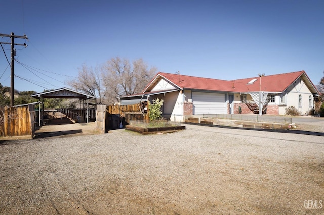 ranch-style home featuring a garage, fence, a tiled roof, and a gazebo