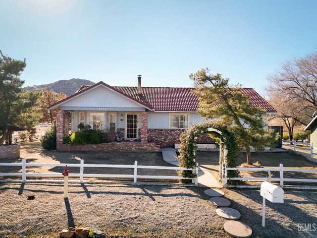 view of front of home featuring a tiled roof, brick siding, and a fenced front yard