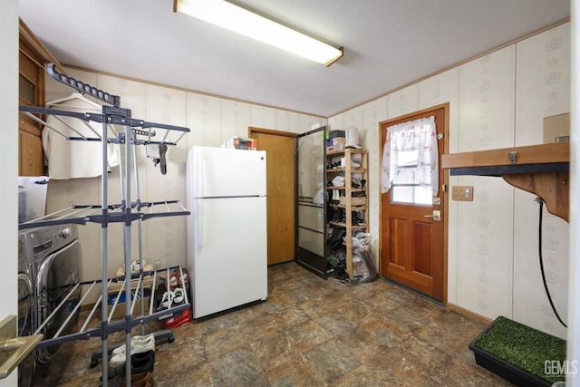 kitchen featuring stone finish flooring, washer / clothes dryer, freestanding refrigerator, and crown molding