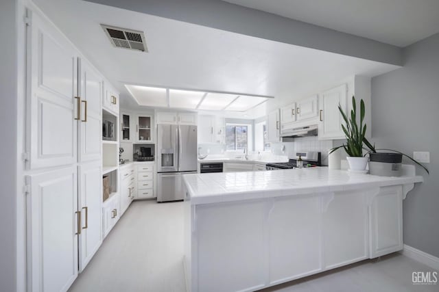 kitchen featuring visible vents, a peninsula, stainless steel appliances, under cabinet range hood, and white cabinetry