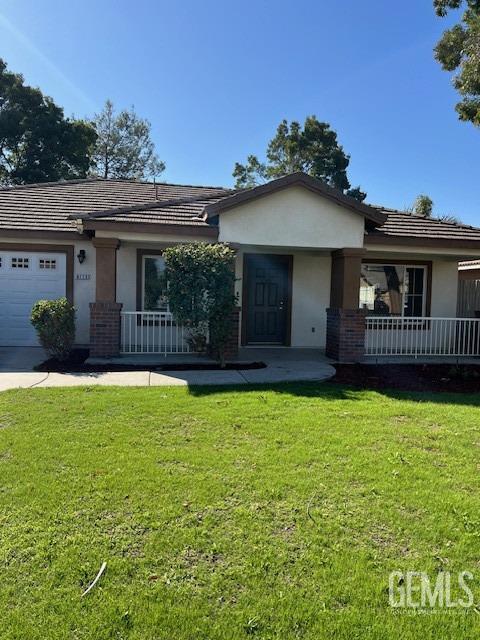 ranch-style house with a front lawn, covered porch, and a garage