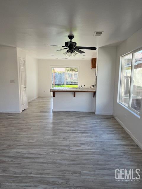 unfurnished living room featuring plenty of natural light, dark wood-type flooring, and ceiling fan