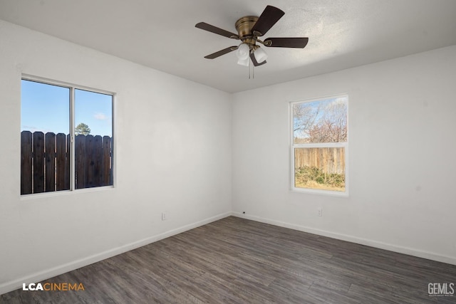 unfurnished room featuring dark wood-type flooring, a wealth of natural light, and ceiling fan