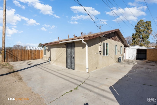 rear view of house featuring central air condition unit and a storage unit