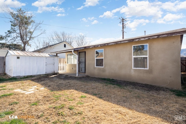 back of property featuring a yard and a storage shed