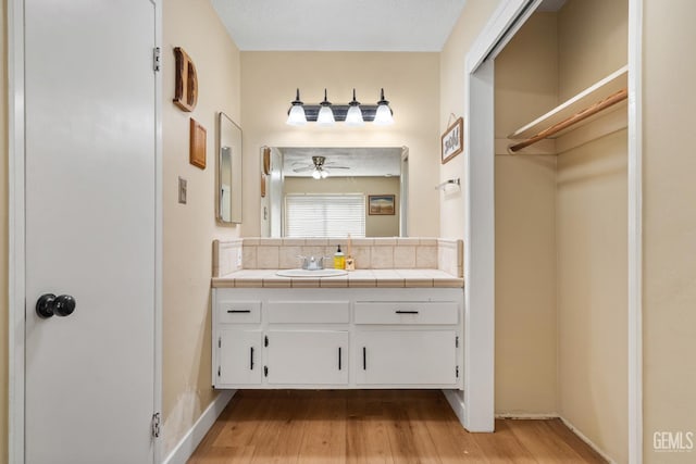 6101 Crestmore St, Bakersfield, CA 93308 - bathroom featuring backsplash, wood finished floors, vanity, and a ceiling fan