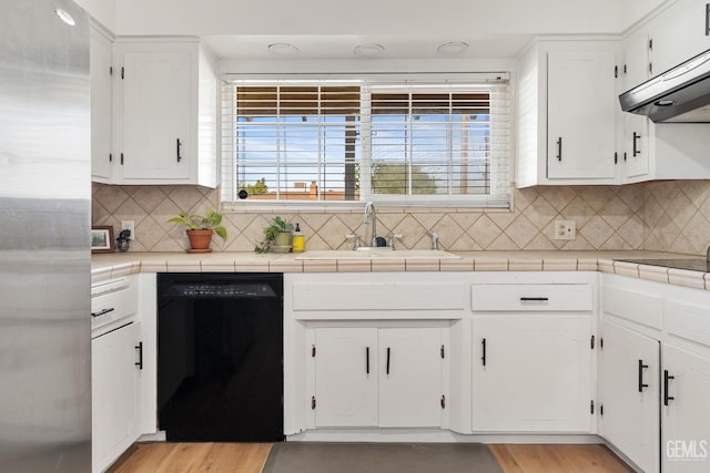 6101 Crestmore St, Bakersfield, CA 93308 - kitchen with black appliances, exhaust hood, white cabinets, tasteful backsplash, and light wood finished floors