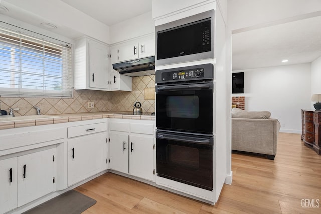 6101 Crestmore St, Bakersfield, CA 93308 - kitchen with black appliances, tile counters, under cabinet range hood, tasteful backsplash, and recessed lighting