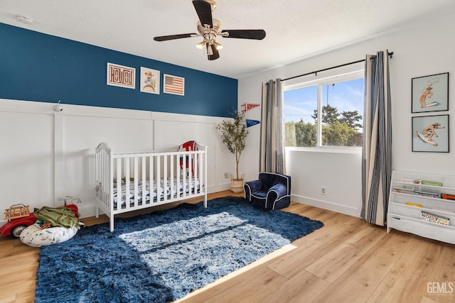 6101 Crestmore St, Bakersfield, CA 93308 - bedroom with wood finished floors, a crib, ceiling fan, and a textured ceiling