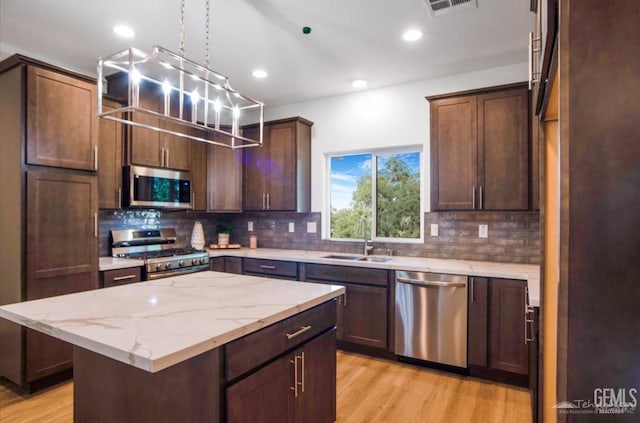 18671 Buckeye Pl, Tehachapi, CA 93561 - kitchen with appliances with stainless steel finishes, backsplash, light wood-style flooring, a kitchen island, and recessed lighting
