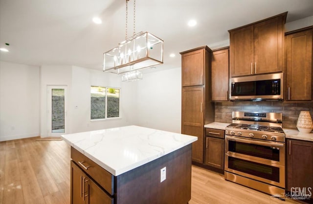 18671 Buckeye Pl, Tehachapi, CA 93561 - kitchen featuring appliances with stainless steel finishes, a kitchen island, backsplash, light wood-style flooring, and hanging light fixtures