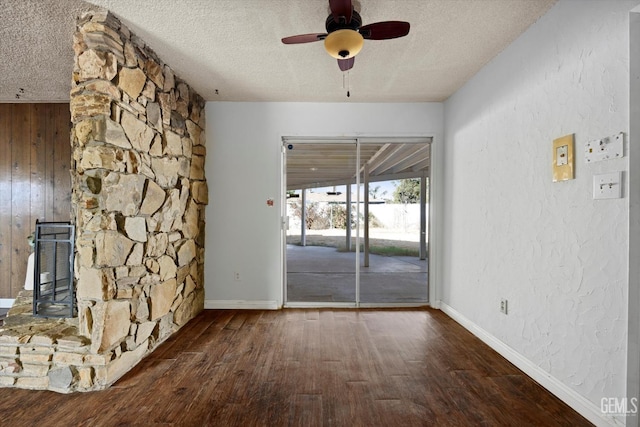 unfurnished living room featuring wood walls, dark hardwood / wood-style floors, ceiling fan, and a textured ceiling