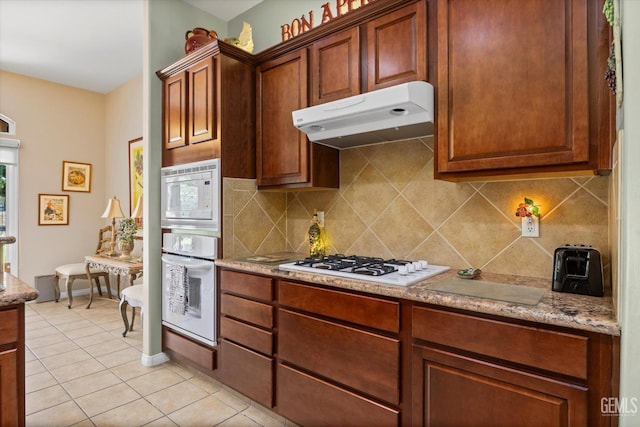 9005 Via Lugano, Bakersfield, CA 93312 - kitchen with white appliances, under cabinet range hood, light tile patterned floors, and tasteful backsplash