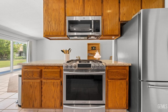 10400 Walnut Creek Ct, Bakersfield, CA 93311 - kitchen featuring appliances with stainless steel finishes, light tile patterned flooring, brown cabinets, and light stone countertops